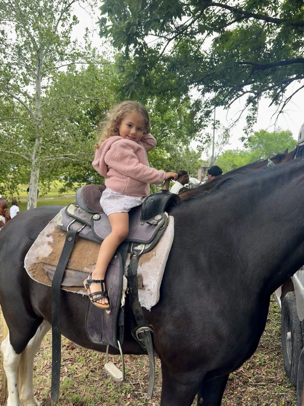 A young child smiling while riding a horse
