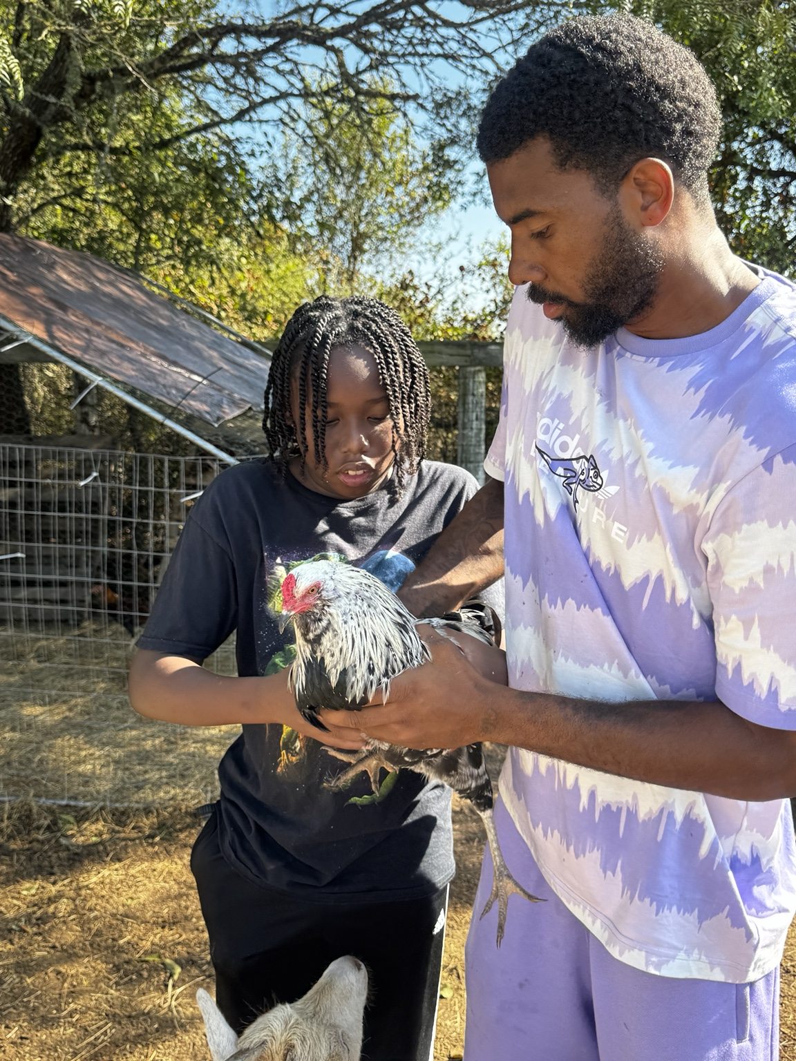 Two visitors learning to handle a chicken together